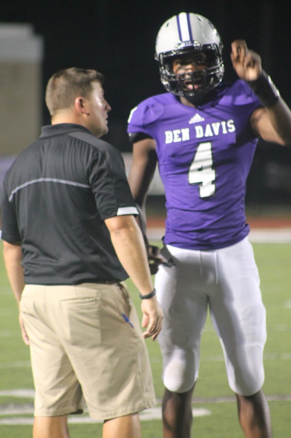 Assistant football coach Justin Faires talks to quarterback Azjai Cooper during the Cathedral game. Faires played on two state championship teams while a student here.