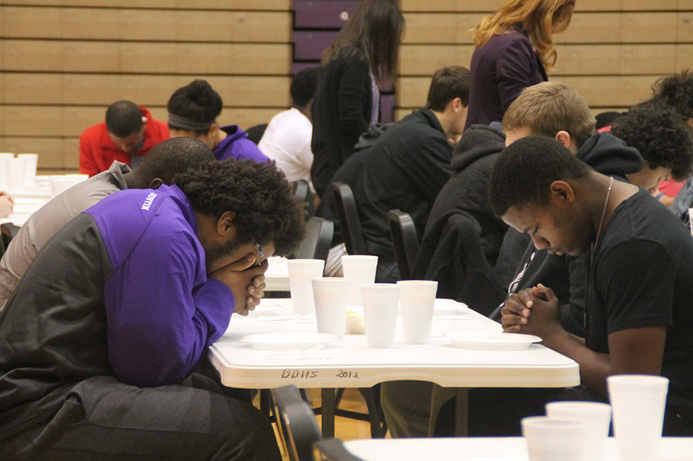 Demarco Henry (right) prays during the state breakfast prior to the 2014 state football game. Henry is the new strength coach at Ben Davis.
